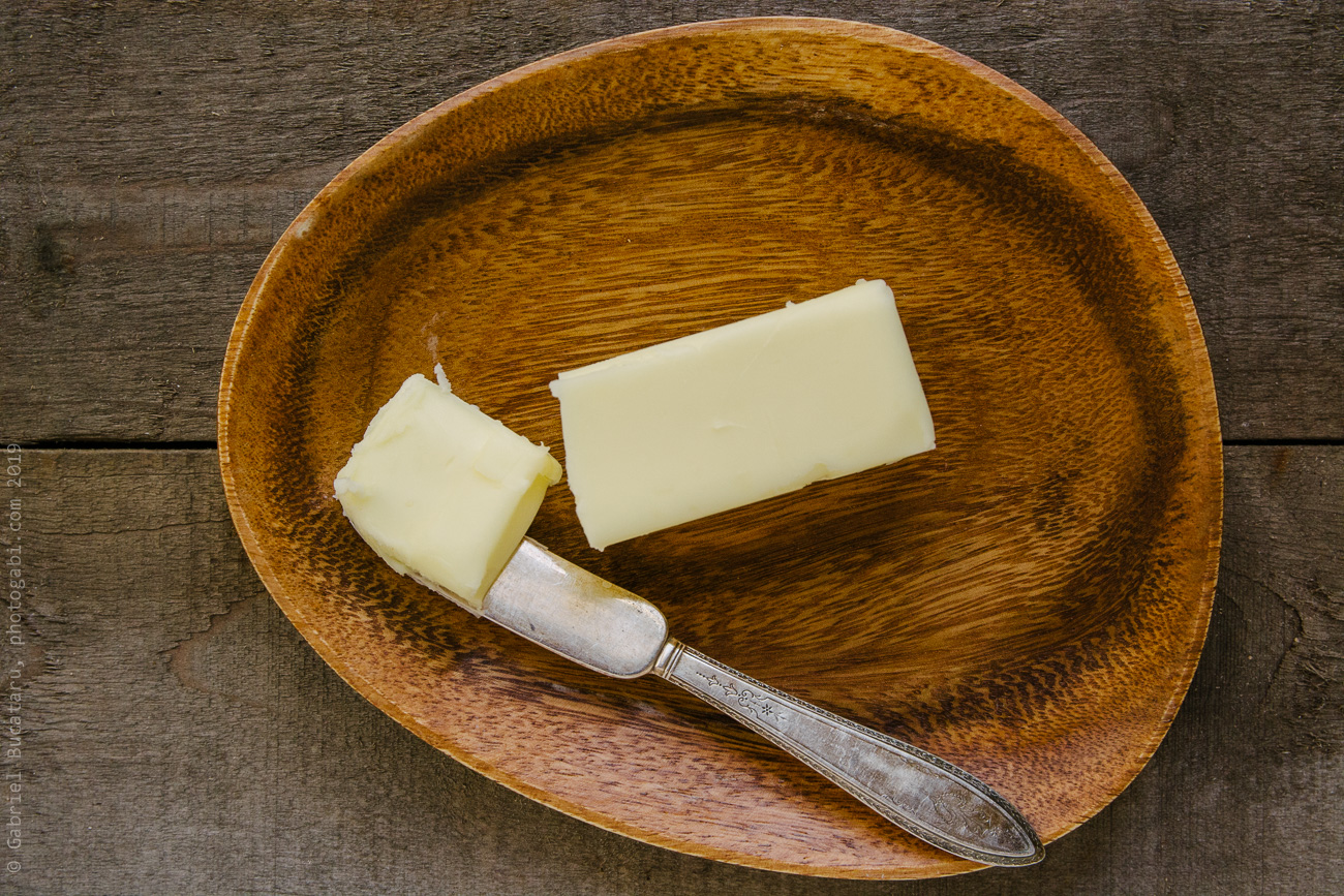 Stick of butter on a wooden plate with knife